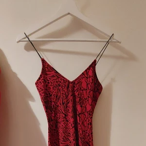 Tight röd/svart klänning - Tight, smal klänning, röd med svart mönster. Knappt använd.