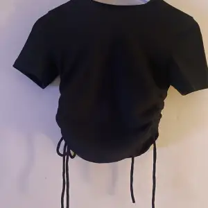 Svart t-shirt med knytning (resor) på sidorna  Ribbat material Bra skick 