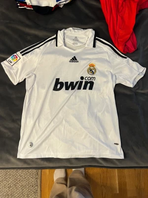 Fotbollströja  - T-shirt från adidas med real Madrid tryck. Som ny, aldrig använd. Kan mötas upp annars står köparen för frakt! 