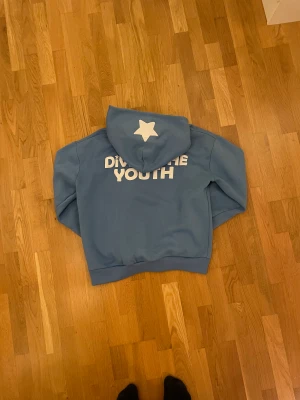 Divide the Youth hoodie - Sparsamt använd hoodie, skick 8/10. Säljer den för att den inte längre passar min garderob:) Storlek L passar boxy, färg ljusblå 