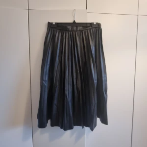 Knälång skinkjol från Lindex - Plisserad knälång skinkjol från Lindex. Storlek S