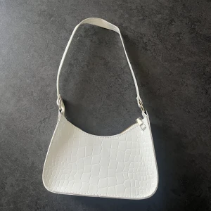 Mindre hanväska - Handväska i axelmodell, rymmer telefon, nycklar, plånbok osv.  Vit snake print  Okänt märke  Sparsamt använd