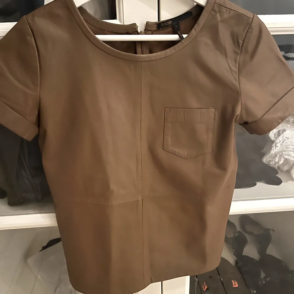 Så Nice brun/beige Maje t-shirt i läder! Köpte på sellpy för 1000 och säljer för 800💘 Oanvänd av mig och i jätte bra skick . T-shirts.