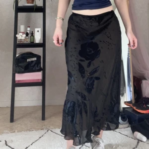 Klänning/kjol - Svart plagg som kan användas som både klänning och kjol, blommigt mönster i satin och pärlor, har ett beiget undertyg 