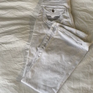 Vita bootcut jeans - Vita lågmidjade bootcut jeans.Okändt märke,vintage med coola diamant tryck på fickorna bra skick men knappen är dock lite lös men tror lätt man kan fixa det skriv för mer info eller fler bilder.Det står ingen storlek på men passar mig som andvänder 34/36.