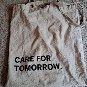 Tygväska - Säljer denna beiga tygväska med texten "care for tomorrow" för 69 kr. Så söt till sommaren. Varken för liten eller för stor. Ingen innerficka, men man kan fixa en själv. 