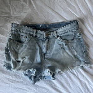 Ljusblå jeansshorts - Ljusblå jeansshorts med slitningar! I mycket bra skick. Märket på jeansshortsen samt storleken har försvunnit men skulle uppskatta att det är en XS.
