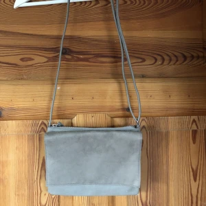 Grå axelväska  - Grå axelremsväska med justerbara band. Aldrig använd. Frakten ingår i priset💚