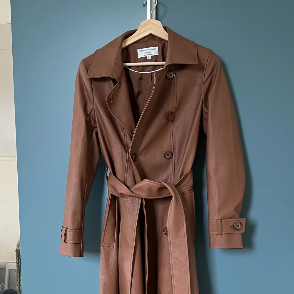 Helene Berman- brun trenchcoat i läderimitation. Sälja på ASOS för 1200kr och är slutsålt på hemsidan. Har bara använts en gång och är som ny. Sitter super snyggt på och perfekt att ha en tjocktröja eller hoodie under. . Jackor.