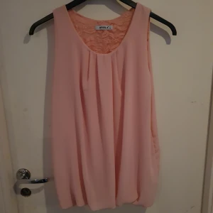 Rosa blus - En rosa blus u skönt tyg, känns som L men lite pösig. Har öppen rygg med spets. Bra skick nästan oanvänd och mycket fin. Osäker på märket syns dåligt på lappen.
