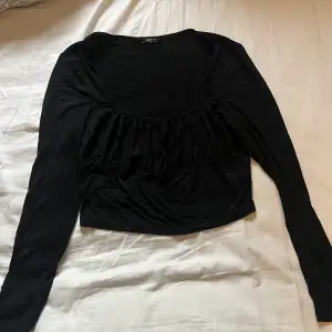 En svart tröja som är ganska låg vid brösten. Går att knyta vid brösten för att justera storlek. 