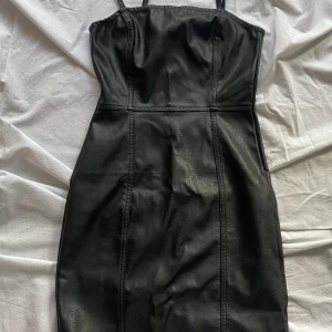 Svart Cocktail klänning  - Cocktail klänning i svart konstläder (Fake). Sitter som en smäck på kroppen. Kanske passade till halloween.