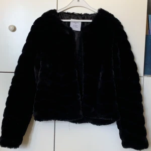 Fluffig svart kofta  - En fin festligare kofta i nyskick. Bara använd ett par få gånger. Det finns knappar i som går att knäppa. 