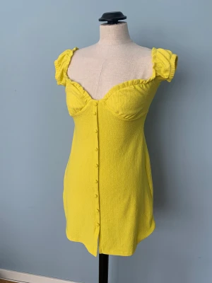 Mini klänning - Jättesöt gul klänning från Pull&Bear, strlk S. Knapparna går inte att öppna men matrialet är jätte stretchigt och skönt! Klänningen är köpt från Sellpy i gott skick. Den har tyvärr inte kommit till användning för mig, därför säljer jag vidare den.