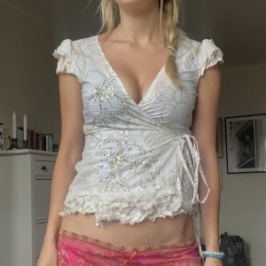 Y2K blus - Vit blus med blommor som man knyter omlott. 