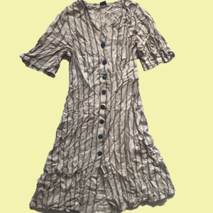 Randig klänning - Beige randig klänning som når ner till vaden. Väldigt tunnså skulle vara skön att ha till vardags. Köpt för några år sedan men aldrig använd. 