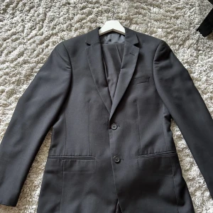 Kostym från dressman - Kavaj och kostymbyxor köpta på dressman i en slimfitt model. Väldigt fint skick, använda ett fåtal gånger.  Kavaj storlek 44 Kostymbyxor storlek 28x32.