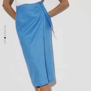 Linnekjol blå - En oanvänd blå midi linnekjol från mango. Det är en omlott kjol med knapp och knyte på sidan. 100% linne. Storlek: M Nypris: 399