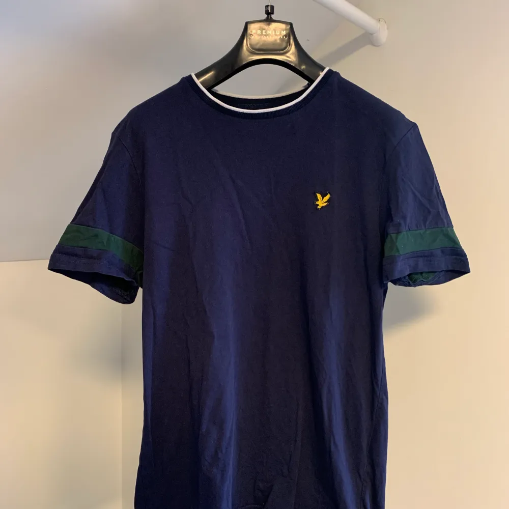 En mörkblå Lyle & Scott t-shirt i storlek S.  Mönster på både kragen och ärmarna där passformen är normal. T-shirts.