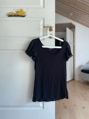 Tröja med volang  - Svart tröja med volang på ärmen 