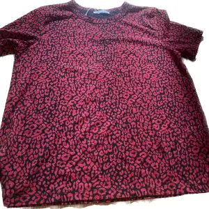 Röd och svart leopardmönstrad t-shirt med texten ”follow your intuition” (som förövrigt knappt syns?) 