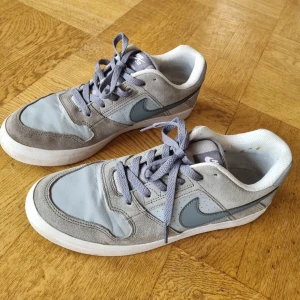 Nikeskor - Ett par fina gråa Nike SB-skor, passar mig som brukar ha strl 39 men kan nog passa en strl 40 också :) Använda men i fint skick, har några små fläckar på insidan av ena skon (se första bilden)🌷 Säljer eftersom att jag inte får användning för dem!