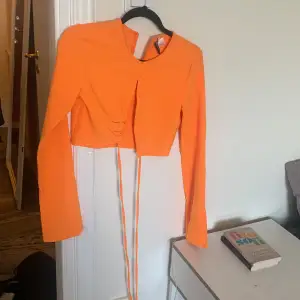Croppad tröja som går att knyta i fin orange färg. Inga tecken på användning.