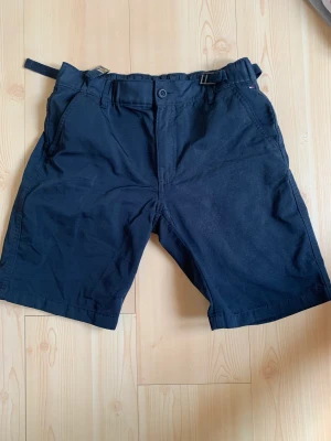 Tommy Hilfiger shorts  - Mörkblå Tommy Hilfiger shorts, använda 2 gånger och därmed i mycket fint skick, storlek en passar 12-13 år 