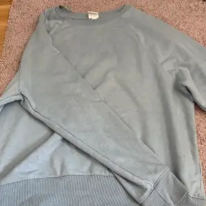 En blå sweatshirt ifrån H&M. Finns en liten gul fläck på armen men kan säkert gå bort i tvätten. 