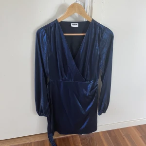 Noisy May finklänning - Klänning med låg urringning och blå-skimmer material. Inte stretchigt material men dragkedja i sidan. Köptes på Vera Moda till nyår men användes ej  (175kr)