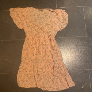 Rosa klänning med blommor  - Volang klänning med blommor på, bra skick dessvärre aldrig kommit till användning 