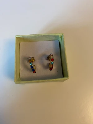 Guldiga örhängen  - Jättefina örhängen med färgade stenar. Två gula stenar på en örhängen har trillat av men det märker man inte när man har på sig örhängena!  10kr+15kr frakt❤️