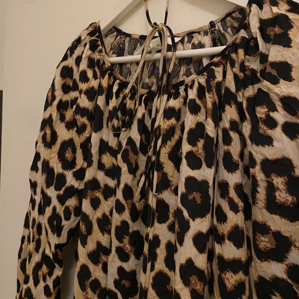 Klänning med leopardmönster från H&M. Loose fit med tillhörande snöre som går att knyta runt midjan för att få  mer figur på klänningen.  Knappt använd, mycket gott skick.  Stor i storleken dock något tight i resåren på ärmarna. Passar även en ”M”. Klänningar.