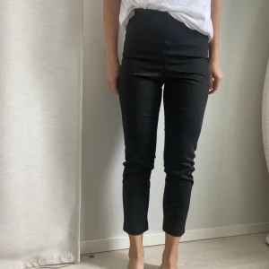 Svartglittriga byxor XS - Svartglittiga ankellånga byxor i stretchigt material från gina tricot. Ränder i sidorna, tyget som randen är gjord av har gått upp lite i sömmen på vänster sida men syns knappt/går att sy!