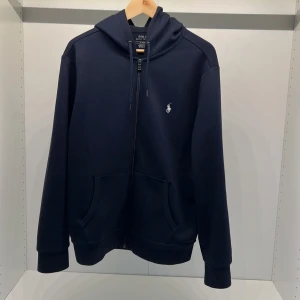 Ralph Lauren hoodie - Säljer en mörkblå Ralph lauren zip hoodie i storlek M som är lite för stor för mig, använd fåtal gånger och är så gott som i nyskick. Nypriset ligger kring 1800 men mitt pris är 800.