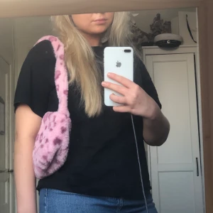 Väska - Rosa luddig väska, med hjärtan på. Helt ny och aldrig använd. Köpte den för 60kr säljer för 20kr. Frakten beroende på hur köparen vill skicka.