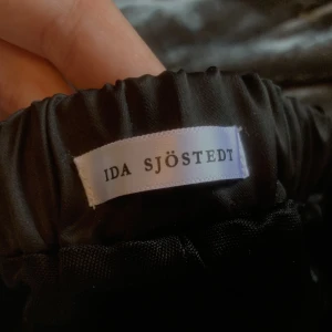 Byxor- Ida Sjöstedt - Svartglittriga, vida, Ida Sjöstedt-byxor i storlek 34. Endast använda en gång då dem egentligen är alldeles för långa för mig. Jag är 173cm och det krävdes runt 10cm höga klackar för att de inte skulle släpa i marken.😬 Midjan passar däremot perfekt.