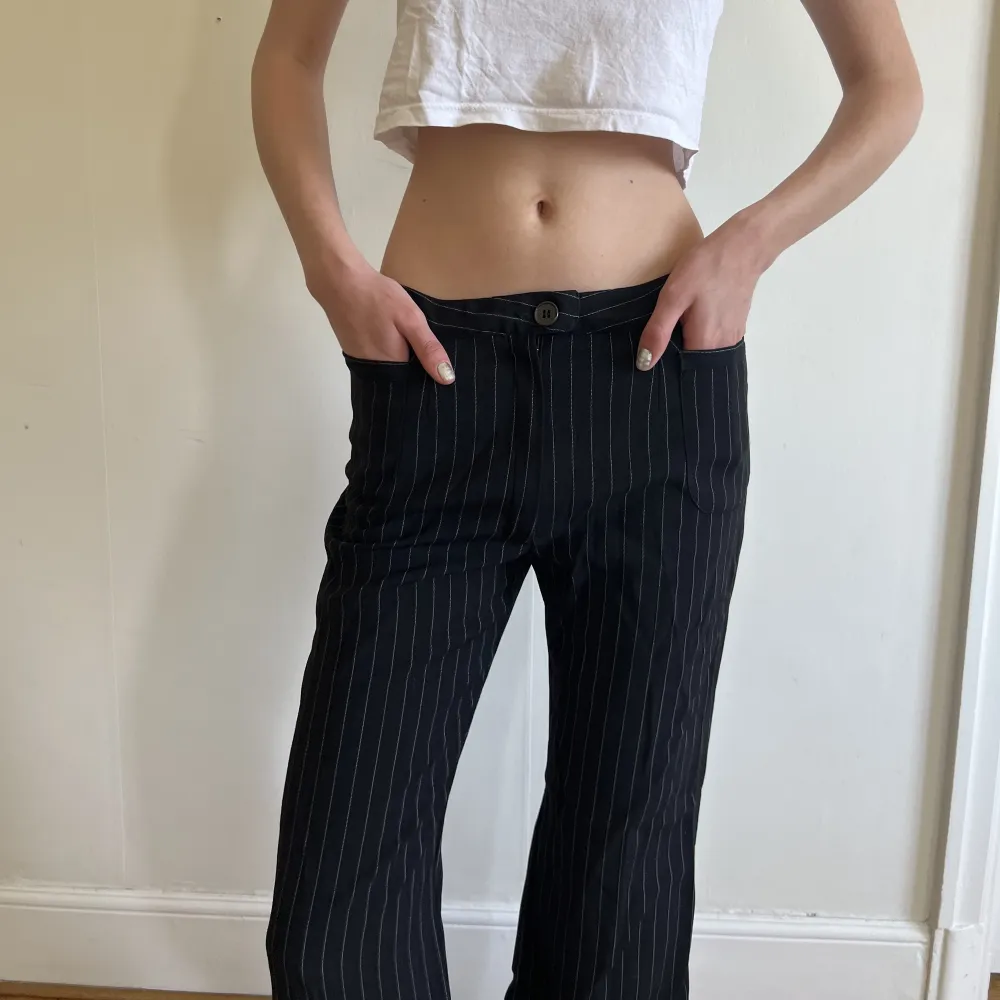 Svarta low-waisted kostymbyxor med vita ränder och fickor. Jag är storlek XS/S . Jeans & Byxor.