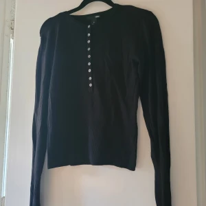 Långärmad finstickad tröja stl.S - Svart finstickad tröja med pärlemorknappar fram. Stl. S. Tightare modell. Sparsamt använd,  fint skick.