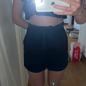 Marinblå shorts - Marinblåa shorts från BikBok, stolen 36. Högmidjade och perfekta till sommaren. Använda 1 gång och därav är så gott som nya. Knytband i midjan, men har även knapp och dragkjedja. Bandet i midjan går att ta bort. 💘