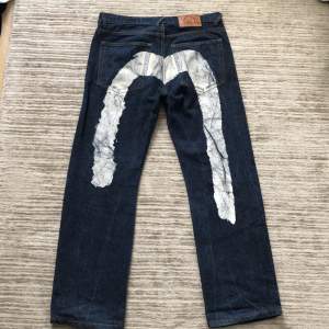 Ett par tvär feta baggy evisu jeans med  tryck på baksidan. Bra skick men använda  24 cm benöppning