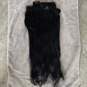 Svart clips löshår  - extensions  Färg: Jet black  Gram: 290 Längd: 60cm men har klippt av håret lite så det är ungefär 50-55 Det är äkta löshår!  Håret är i jätte bra skick inte slitet och vårdad endast med extensions produkter. 