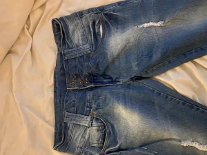 Lågmidjade jeans - Svinsnygga, blå, lågmidjade jeans. De är raka i modellen. Storlekslappen finns inte kvar men skulle säga att de passar folk med 36/38 i jeansstorlek. Fin design på bakfickorna och coola slitningar på benen. Frakt tillkommer, kan även mötas upp i Stockholm
