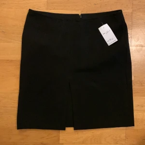 Minikjol - Svart minikjol med slits framme mellan låren. Lite liten i storleken. Något stretchigt tyg. Köpt på Humana men oanvänd av mig pga fel storlek 