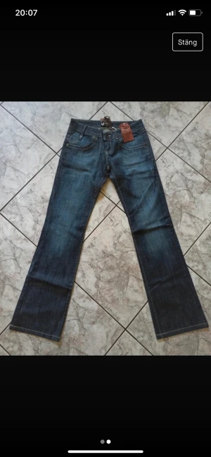 Lågmidjade Y2K jeans  - Lågmidjade jeans. W:31 L:34. Skulle dock säga att de är ganska tajta i midjan för att vara 31. Midjan är 72 och innerbenslängd är 87.  Vita sömmar. En liten kedja tillkommer. Köpta på Vinted med lapp kvar. Ej använda av mig pga fel storlek. Är S/M i midja