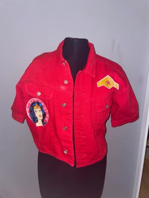 Handmålad t-Shirt jacka  - En fin röd jacka med egen handmålning (inte jag som målat) färgen har hållit länge och kommer fortsätta det. Tålls inte bli tvättad för ofta. Den är en jeans jacka utan långa armar. 