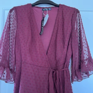 Röd omlottklänning - Vinröd omlottklänning perfekt för sommaren! Aldrig använd, lappen sitter kvar. Från Boohoo