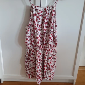Byxdress - Byxdress. Linne och kortbyxa i ett stycke.  Snörning bak. Lite öppen rygg. Blommig i vitt och rött. Divided/ H&M. Fickor i shortsen. Djur- och rökfritt hem. 