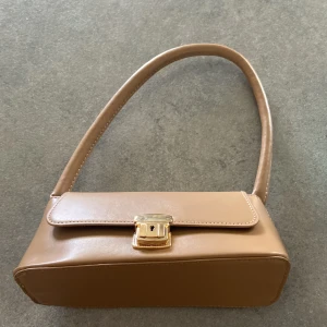Beige väska - Beige väska med guld detaljer, säljer för jag inte använder den 💗Inga defekter, kan skicka mer bilder om det behövs💘