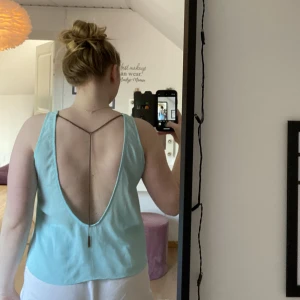 Ljusblå linne med öppen rygg - Ljusblå linne i siden med öppen rygg och metall kedja i brons som går att ta av, stl S men passar allt från S-L, jag är M. 